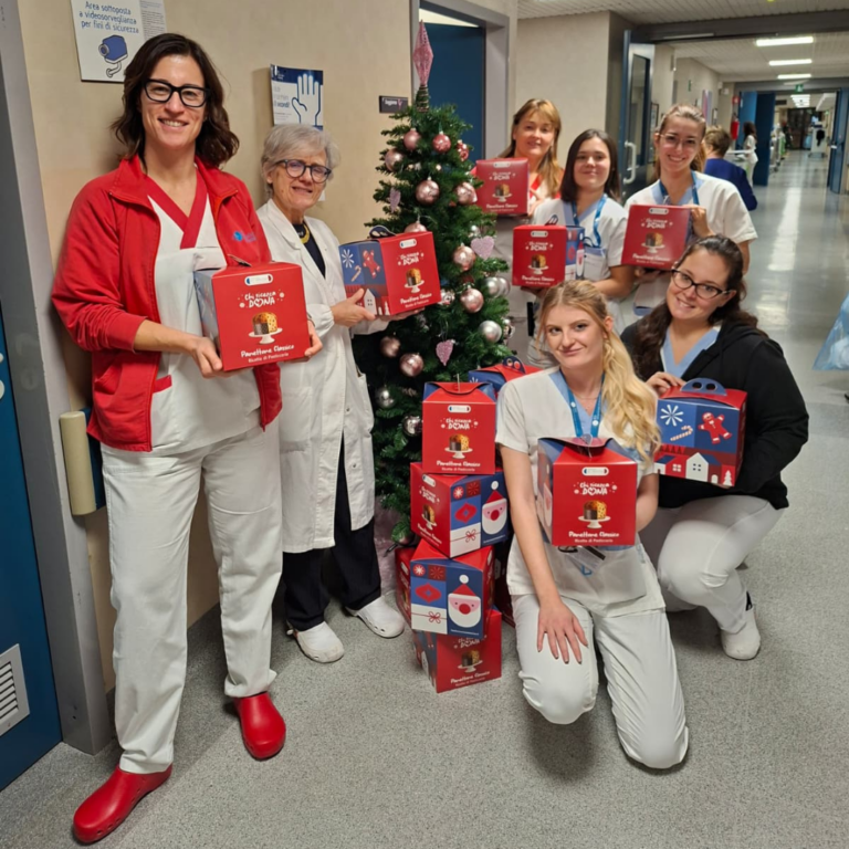 Immagine di un gruppo di infermiere sorridenti che tengono in mano i panettoni della Fondazione IEO-MONZINO