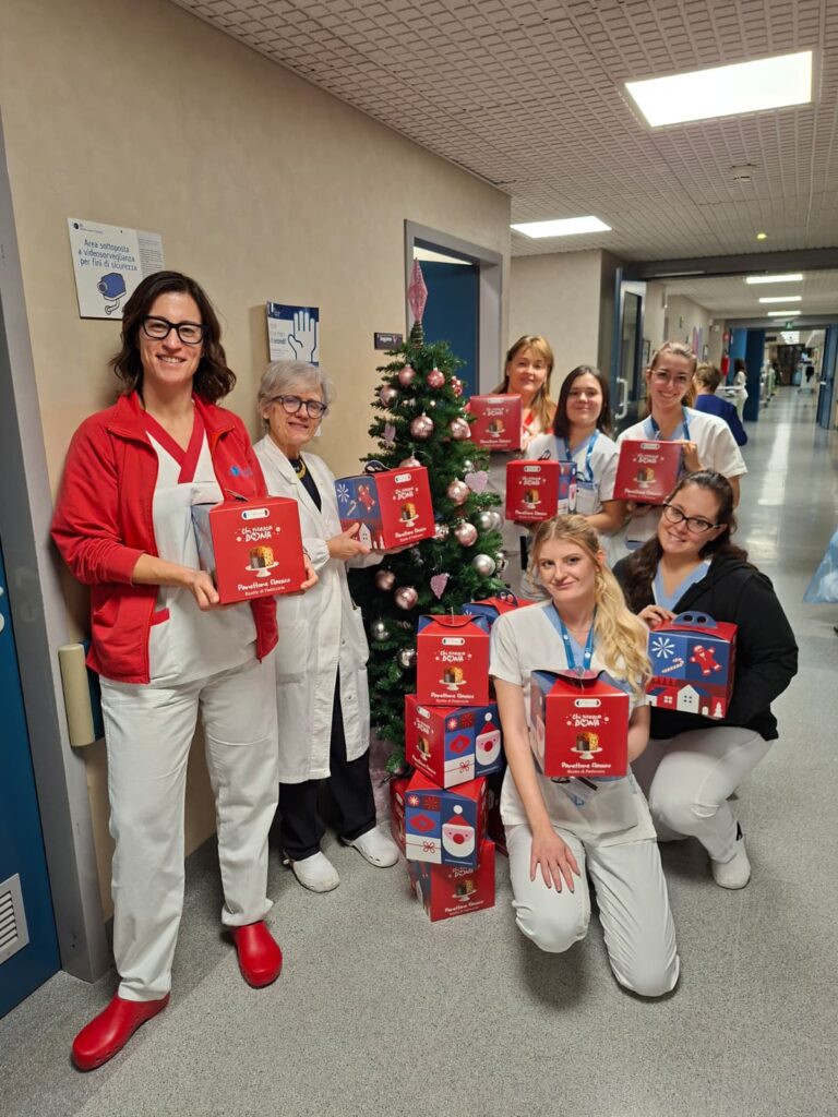 Immagine di un gruppo di infermiere sorridenti che tengono in mano i panettoni della Fondazione IEO-MONZINO